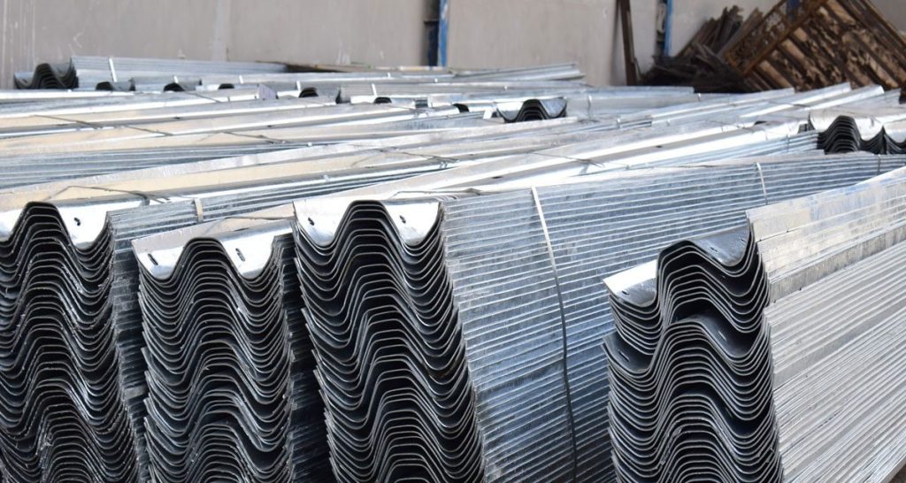 Stacks of hot-dip galvanized W-beam guardrail profiles in the factory yard